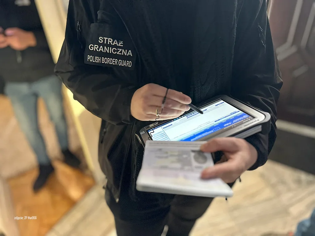 Funkcjonariusz Straży Granicznej sprawdza dokumenty za pomocą tabletu.
